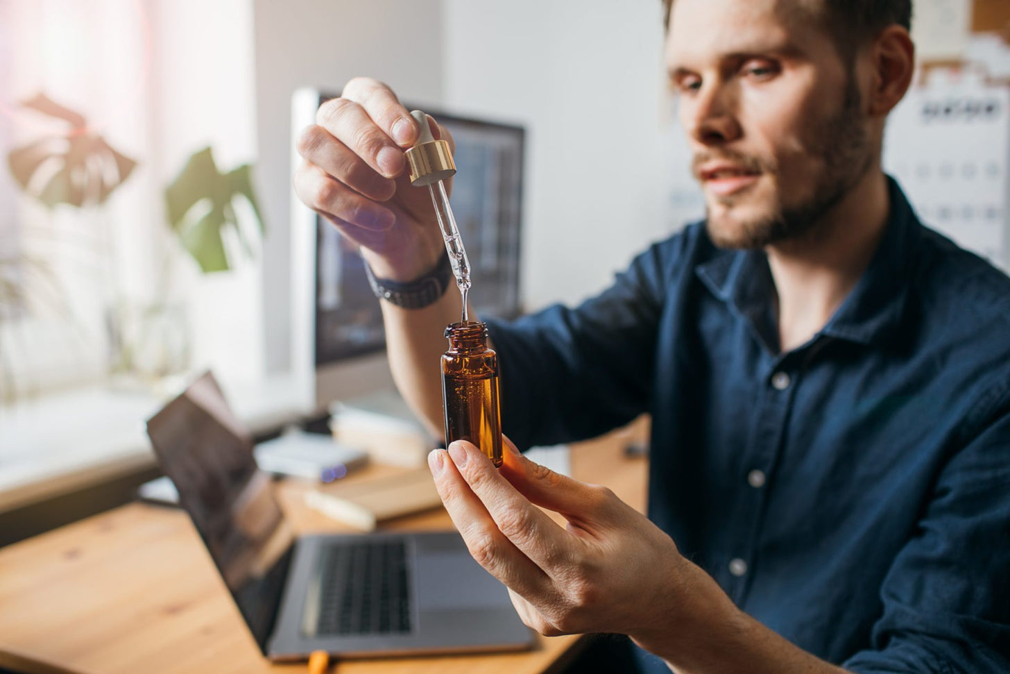 A man holds up a CBD oil dropper and bottle
