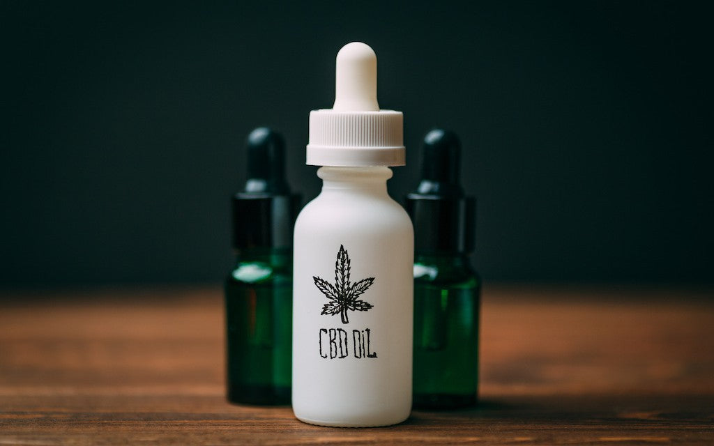 three bottles of CBD oil clustered together against a dark background