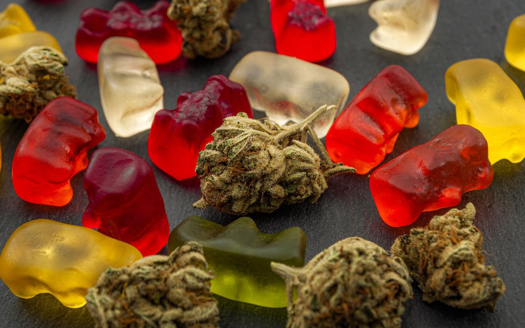 Red, yellow, and white gummy bears strewn amidst hemp flowers