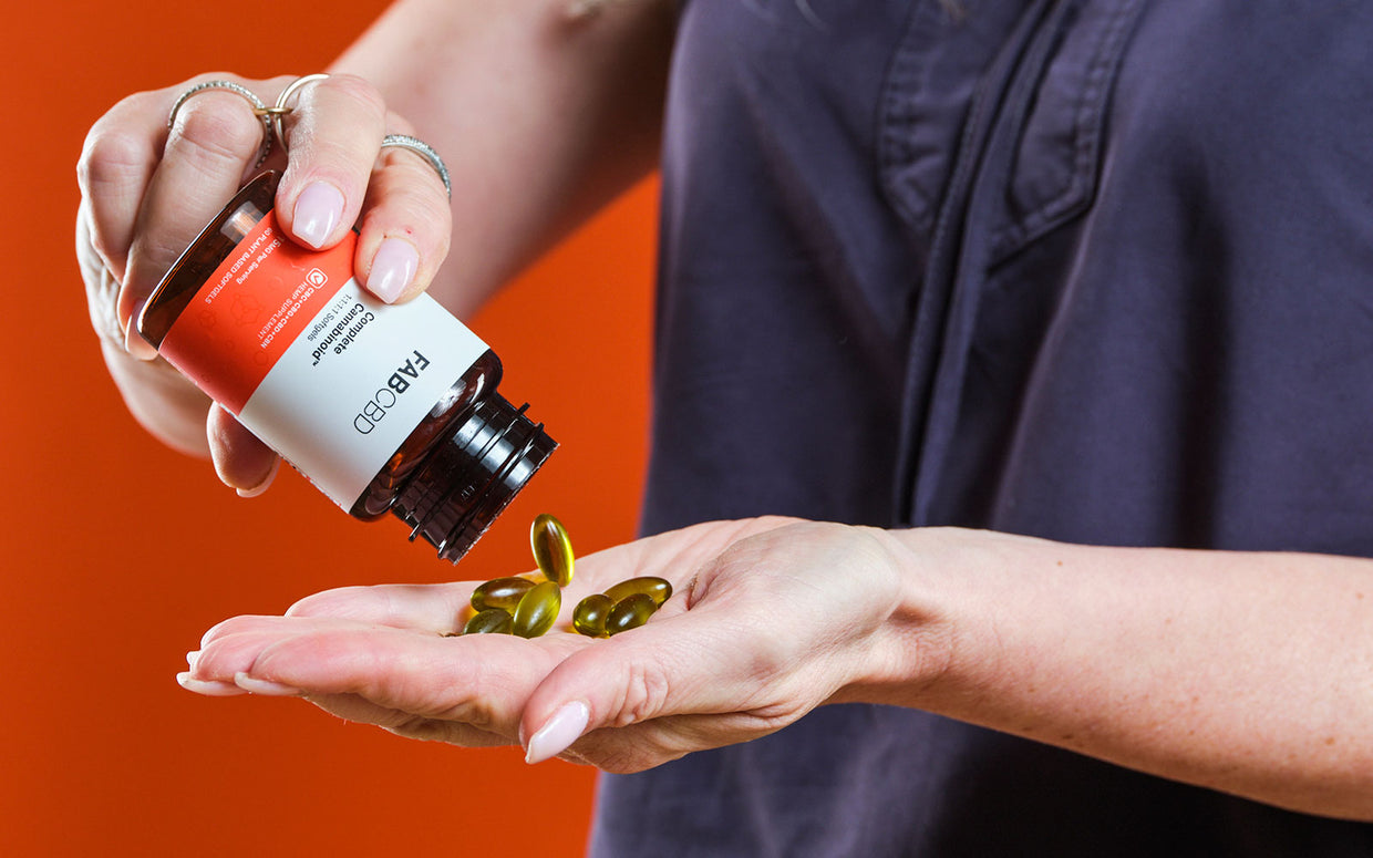 man dispending cbd capsules into hand