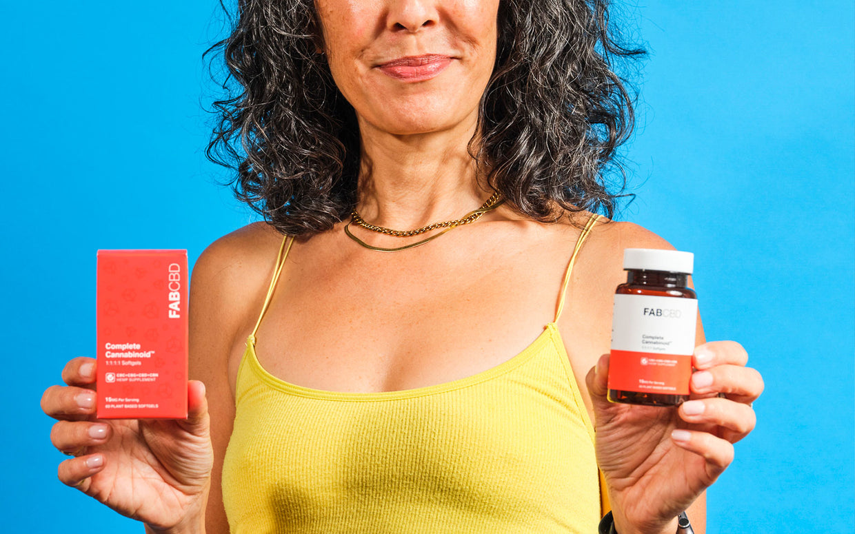 woman holding up a box and bottle of fab cbd capsules