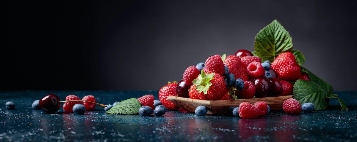 A pile of strawberries, raspberries, blueberries and mint leaves