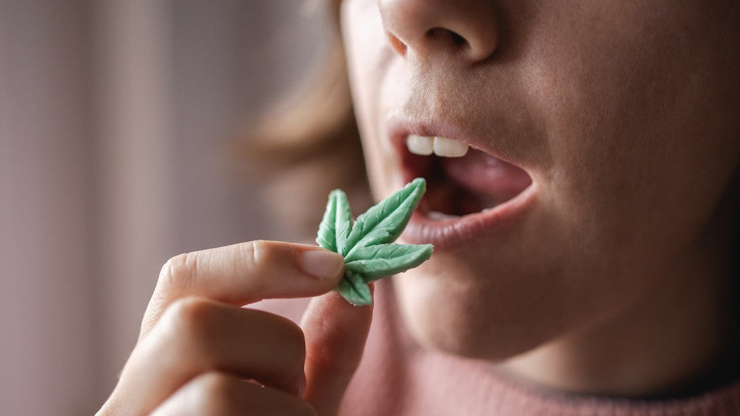 Close-up shot of a woman's face, and she is placing a cannabis leaf-shaped candy into her mouth