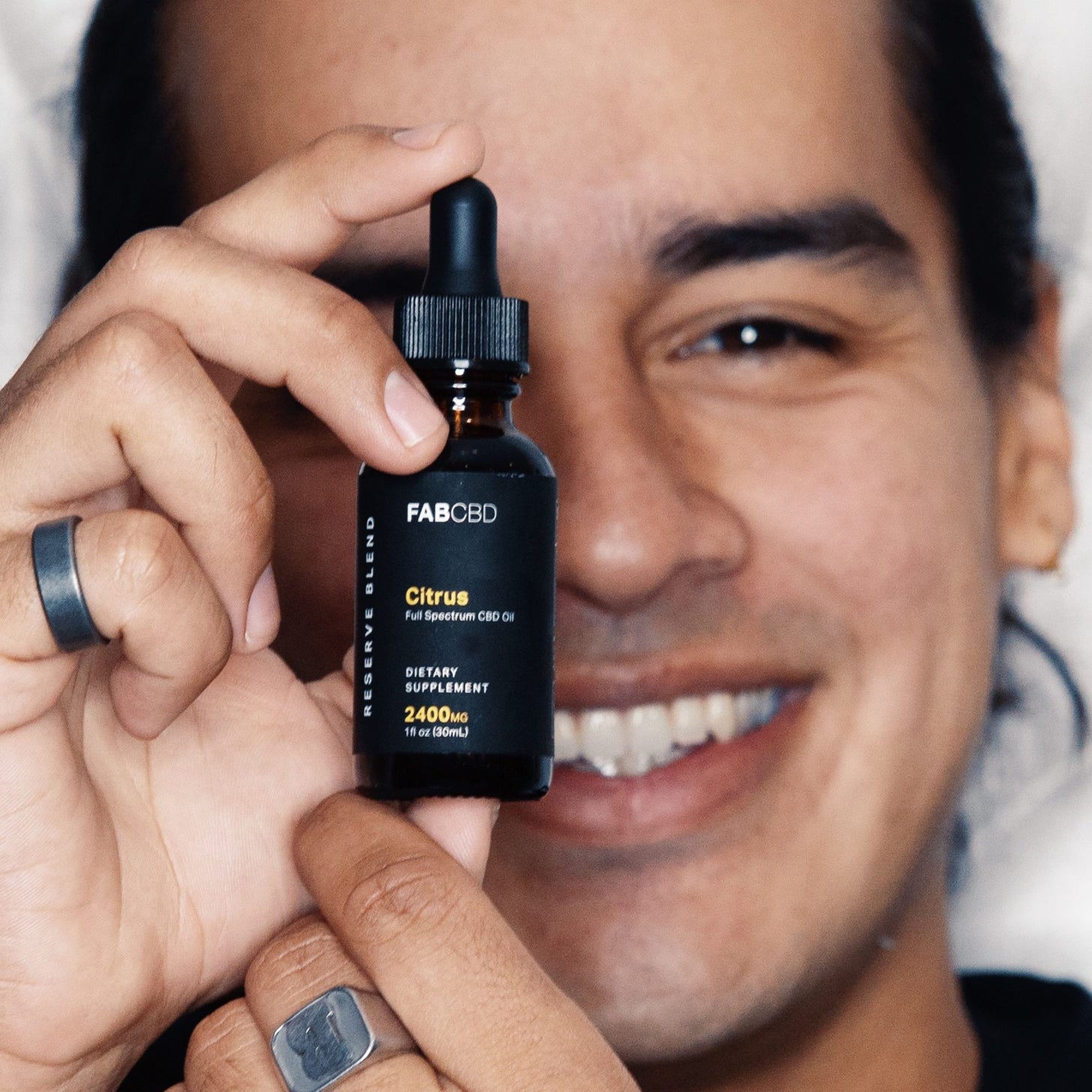 Fab CBD Oil Tincture held in front of a smiling man's face