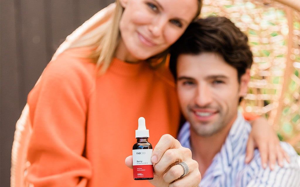 man and woman holding a bottle of CBD oil