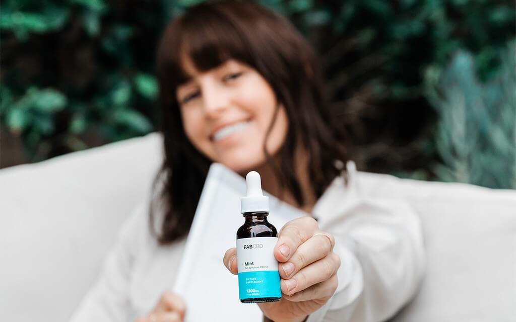 woman holding a bottle of fab cbd oil