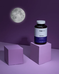 Dark blue bottle of Fab CBD Pill Chews on a lavender cube with a full moon backdrop on deep purple background.