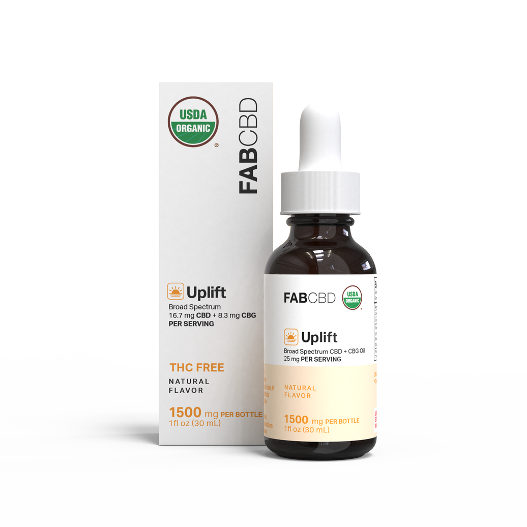 A close-up of a FAB CBD amber dropper bottle and its white box showing "Uplift" label, USDA Organic badge, and dosage text