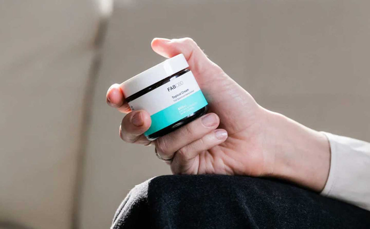 person holding jar of topical CBD cream