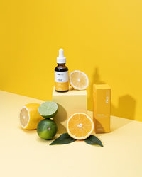 Front view of the CBD Oil bottle labeled FABCBD Citrus on a yellow pedestal with sliced citrus and matching packaging.