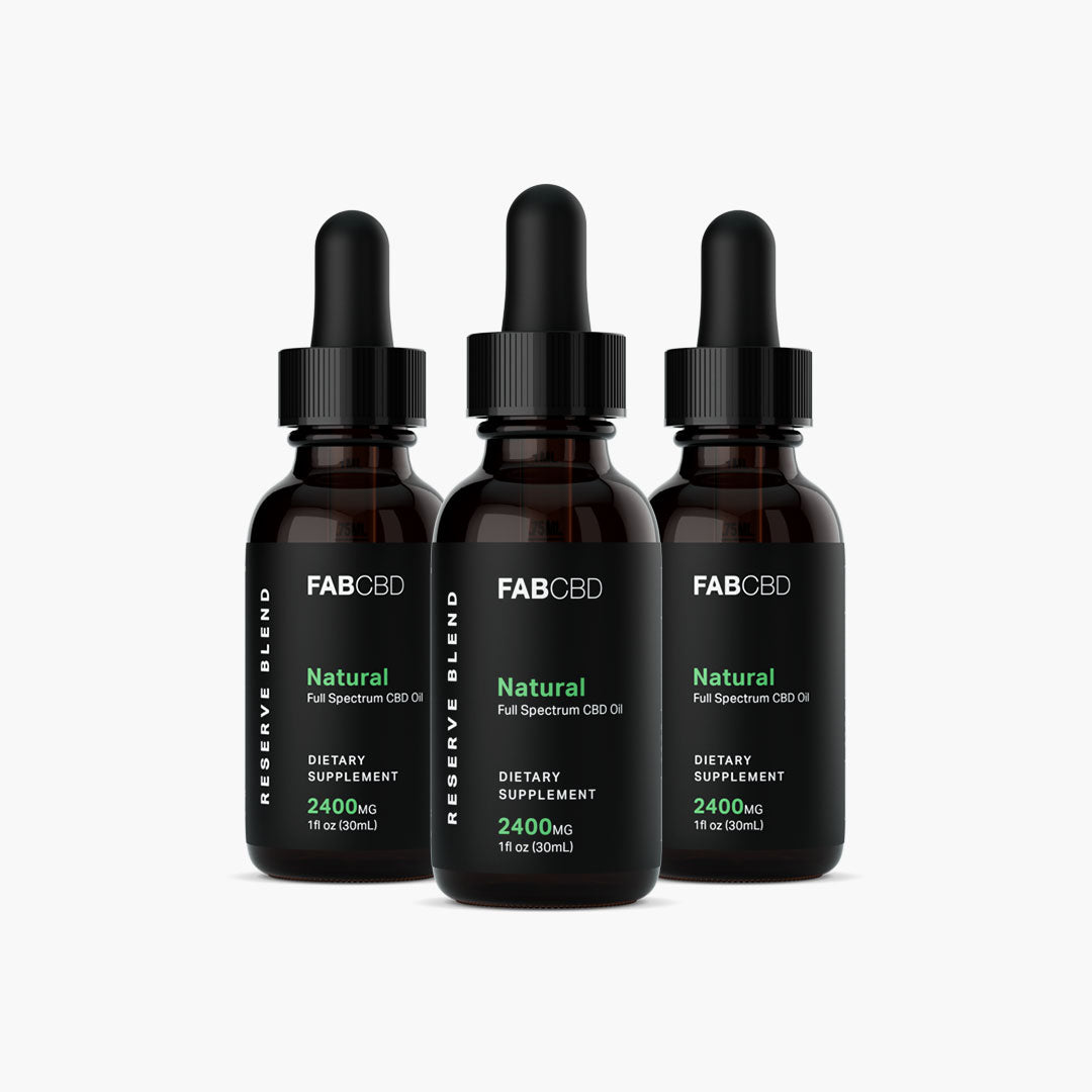 Front view of three FABCBD CBD Oil amber dropper bottles with black labels and green text arranged in a slight arc on a white background.