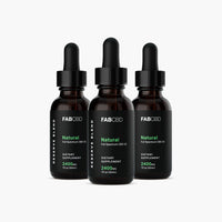 Front view of three FABCBD CBD Oil amber dropper bottles with black labels and green text arranged in a slight arc on a white background.
