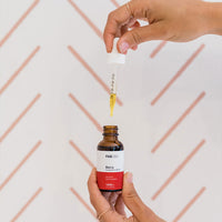 Hands holding a dropper above a brown bottle of CBD Oil, the FAB CBD Oil label reading "Berry" visible against a pale patterned background.